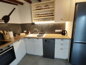 a kitchen with white cabinets and a sink and a refrigerator at Skopelos Mortero Cottage in Panormos Skopelos