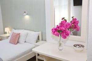 a white room with a table with a vase of pink flowers at Skalopati Studios & Villa in Panormos Skopelos
