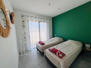 a bedroom with two beds and a green wall at Villa KAÏS in Lecci