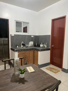a kitchen with a wooden table and a sink at Affordable Apartelle 15mins to the Airport Airport & Sugba Lagoon-Triple Beagle Apartment in Del Carmen