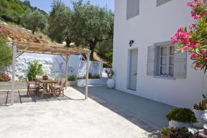 a patio of a white house with a table and chairs at Skalopati Studios & Villa in Panormos Skopelos