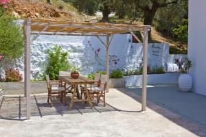 a wooden table and chairs under a pergola at Skalopati Studios & Villa in Panormos Skopelos