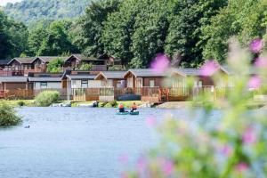 two people in a boat on a lake with houses at Driftwood Lodge - South Lakeland Leisure Village in Carnforth