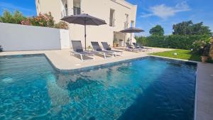 a swimming pool with chairs and umbrellas next to a house at Apartments with Pool Casa Bianca in Matohanci