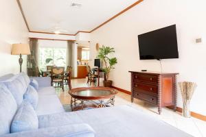 a living room with a blue couch and a flat screen tv at Secluded Garden Paradise Condo @Los Sueños in Herradura