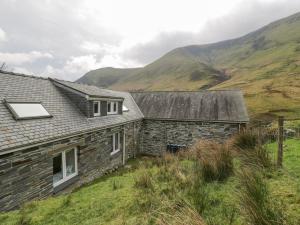 una antigua casa de piedra con montañas en el fondo en Pennant Tigi Uchaf, en Dolgellau