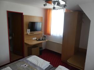 a bedroom with a bed and a desk with a television at Hotel Traube in Sigmaringen