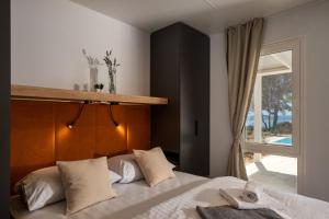 a bedroom with a bed with a wooden headboard and a window at Terra Park Phalaris in Novalja