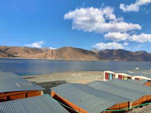 a group of buildings on the shore of a body of water at pangong rainbow cottage in Lukung +23 photos