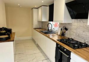 a kitchen with white cabinets and a stove top oven at Glasgow Central Paradise - Spacious 3- Bed House in Glasgow +11 photos