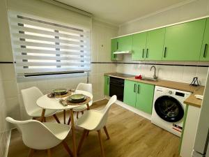 une cuisine avec des armoires vertes et une table et des chaises dans l'établissement Villa Ana, céntrico y tranquilo, parking incluido, à Avilés