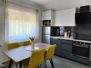 a kitchen with a wooden table and yellow chairs at Happy Moments 2 in Gornje Jesenje