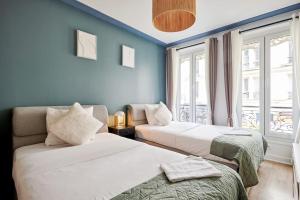two beds in a room with blue walls and windows at Élégance Urbaine - 2 chambres in Paris