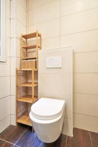 a bathroom with a white toilet and a wooden shelf at Élégance Urbaine - 2 chambres in Paris +22 photos