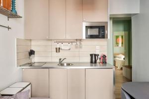 a white kitchen with a sink and a microwave at Élégance Urbaine - 2 chambres in Paris