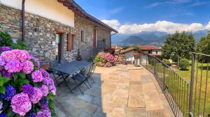 a patio with a table and purple flowers at La Volta - Historic Molino Maufet Watermill - Lake Como in Colico