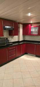 a kitchen with red cabinets and a white tile floor at بورتو مارينا in El Alamein