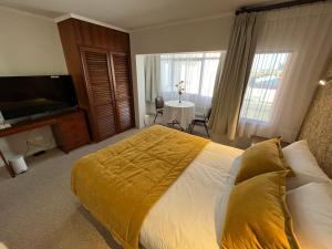 a bedroom with a bed with a yellow blanket on it at Hotel Nicolás Temuco in Temuco