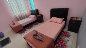 two beds in a bedroom with a stuffed elephant on them at Saujana Homestay Perak in Seri Iskandar