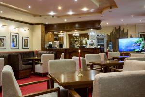a restaurant with tables and chairs and a flat screen tv at Хотел "Калина" in Borovets