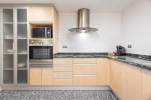 a kitchen with stainless steel appliances and wooden cabinets at Cómodo y luminoso apto cerca de Playas y Valencia in Sueca