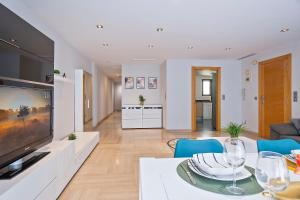 a living room with a television and a dining room at Cómodo y luminoso apto cerca de Playas y Valencia in Sueca