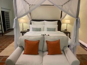 a bedroom with a white bed with orange pillows at Raha Wildlife Resort in Arusha