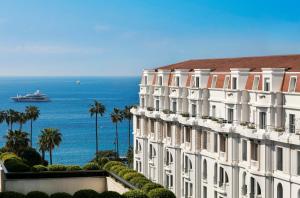 a large white building with a view of the ocean at Hôtel Barrière Le Gray d'Albion in Cannes