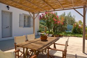 a wooden table and chairs under a wooden pergola at Skalopati Studios & Villa in Panormos Skopelos