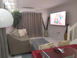 un soggiorno con divano e TV a schermo piatto di The Island Flat Villa - Near Airport & Beach a Montego Bay