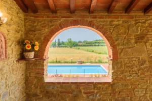 Una ventana en un muro de piedra con una piscina. en Villa Pasqualina by Mmega, en Arezzo