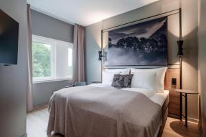 a bedroom with a large bed with a painting on the wall at Quality Hotel Edvard Grieg in Bergen