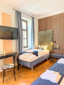 a bedroom with a bed and a tv on the wall at Villa Fantasia Budget Boutique Hotel in Füssen