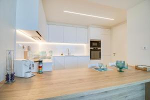 a kitchen with white cabinets and a wooden counter top at Bayline Cond - Sea View - SPA - Pool - GYM - Truta BY BEDZY in Armação de Pêra