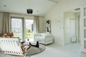 a living room with a white chair and a table at Beau Su Mer nr 1 in Kattendijke