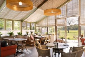 a restaurant with tables and chairs and windows at New Park Manor Hotel - A Luxury Family Hotel in Brockenhurst