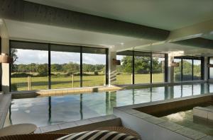 a large swimming pool in a house with windows at New Park Manor Hotel - A Luxury Family Hotel in Brockenhurst