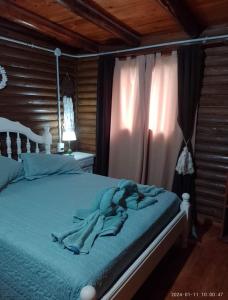 Un dormitorio con una cama con sábanas y cortinas azules. en Amphu, en La Falda