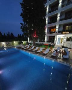 a large swimming pool with lounge chairs and a building at Hotel HOTI II RIZO ULCINJ in Velika Plaža
