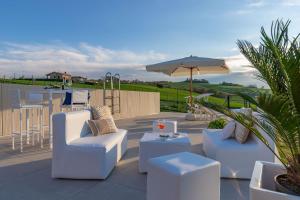 a patio with two white chairs and an umbrella at Italian Experience-Villa Clair in Fermo