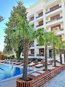 a hotel swimming pool with lounge chairs and palm trees at Hotel HOTI II RIZO ULCINJ in Velika Plaža