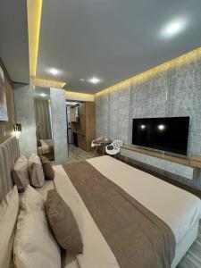 a bedroom with a large bed and a flat screen tv at Badem Garden Apart Hotel in Tashkent