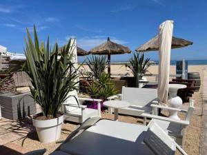 plaży z krzesłami, stołami i parasolami w obiekcie Italian Experience-Numana Suite Apartment w mieście Numana
