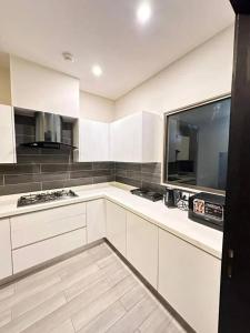 a kitchen with white cabinets and a large window at BNR - The Opus Residences - Studio Luxury Apartment Gulberg in Lahore