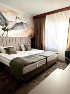 a bedroom with two beds with a bird painting on the wall at Resort Strzelnica in Kochcice
