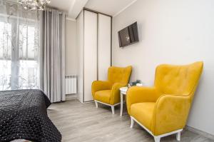 a bedroom with two yellow chairs and a bed and a table at Willa Anavill in Mielno
