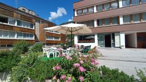 a table and chairs with an umbrella in front of a building at Appartamenti Roulette Montana Marilleva 900 in Mezzana