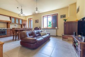 ein Wohnzimmer mit einem Ledersofa und einer Küche in der Unterkunft Italian Experience - Sunrise Hill Holiday Home in Urbisaglia