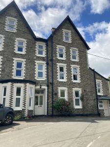 a large brick house with a car parked in front of it at Serenity House Wales in Llangammarch Wells +44 photos