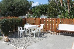 eine Terrasse mit weißen Tischen und Stühlen und einem Zaun in der Unterkunft L'albero Dei Limoni B&B in Taranto